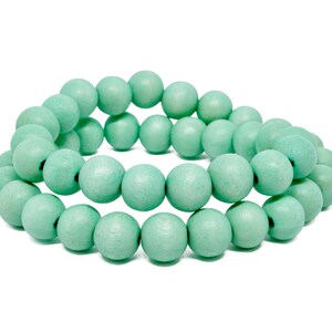 Puede incluir: Un brazalete hecho de cuentas de madera de color verde claro. Las cuentas son redondas y lisas, y est&aacute;n enhebradas juntas en un dise&ntilde;o simple.