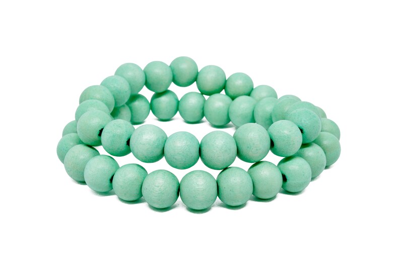 Puede incluir: Un brazalete hecho de cuentas de madera de color verde claro. Las cuentas son redondas y lisas, y est&aacute;n enhebradas juntas en un dise&ntilde;o simple.