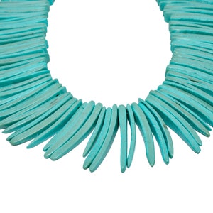 May include: A turquoise blue necklace made of long, thin, curved pieces of turquoise. The necklace is arranged in a fan shape.