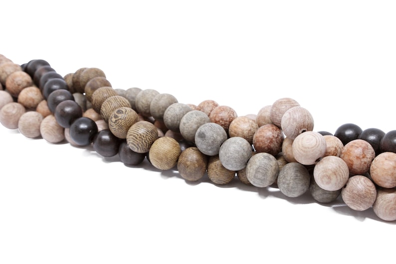 May include: A strand of wooden beads in various shades of brown, gray, and black. The beads are round and have a natural, rustic look.