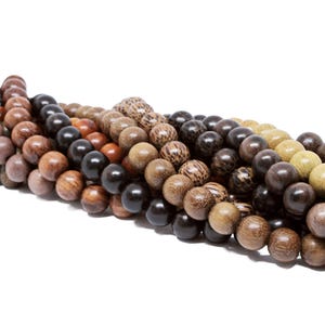 May include: A strand of wooden beads in various shades of brown, black, and beige. The beads are round and smooth, and they are strung together on a cord.