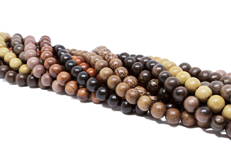 May include: A strand of wooden beads in various shades of brown, black, and beige. The beads are round and smooth, and they are strung together on a cord.