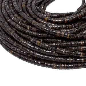 Könnte beinhalten: Eine Schnur aus dunkelbraunen Muschelkernperlen, jede Perle ist eine flache Scheibe mit leicht erhabener Mitte. Die Perlen sind spiralförmig angeordnet und zeigen die Textur und Farbe der Muschel.