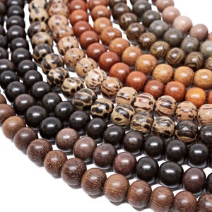 May include: A close-up of a variety of wooden beads in different shades of brown, black, and gray. The beads are arranged in a semi-circle, with the darkest beads at the bottom and the lighter beads at the top.
