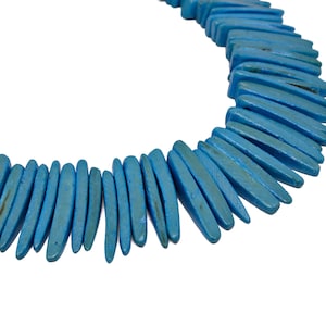 May include: A necklace made of turquoise blue, long, pointed, wooden beads. The beads are arranged in a staggered pattern, creating a unique and eye-catching design.