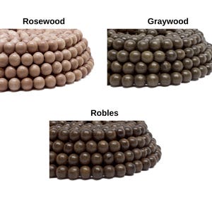 May include: Three piles of wooden beads in different colors: rosewood, graywood, and robles. The beads are round and smooth.