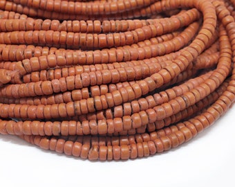 May include: A strand of terracotta-colored beads, made of natural materials, with a smooth, slightly rough texture. The beads are round and uniform in size, creating a consistent pattern.