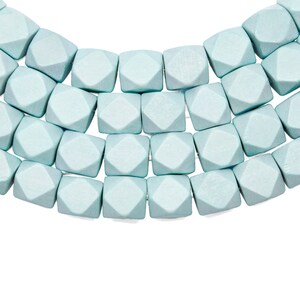 Może przedstawiać: Szereg jasnoniebieskich drewnianych koralików o fasetowanym, geometrycznym kształcie.