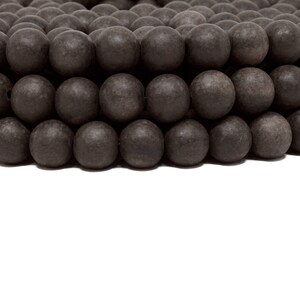 May include: A close-up of a strand of dark brown wooden beads. The beads are round and smooth, and they are arranged in a circular pattern.