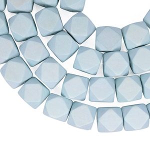 Może przedstawiać: Szereg jasnoniebieskich fasetowanych koralików z kamieni szlachetnych. Koraliki mają kształt sześcianu z diamentowym wzorem na każdej stronie.