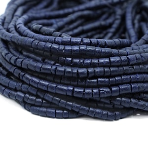 Peut inclure: Un brin de perles en bois bleu foncé. Les perles sont cylindriques et ont une surface rugueuse et texturée.