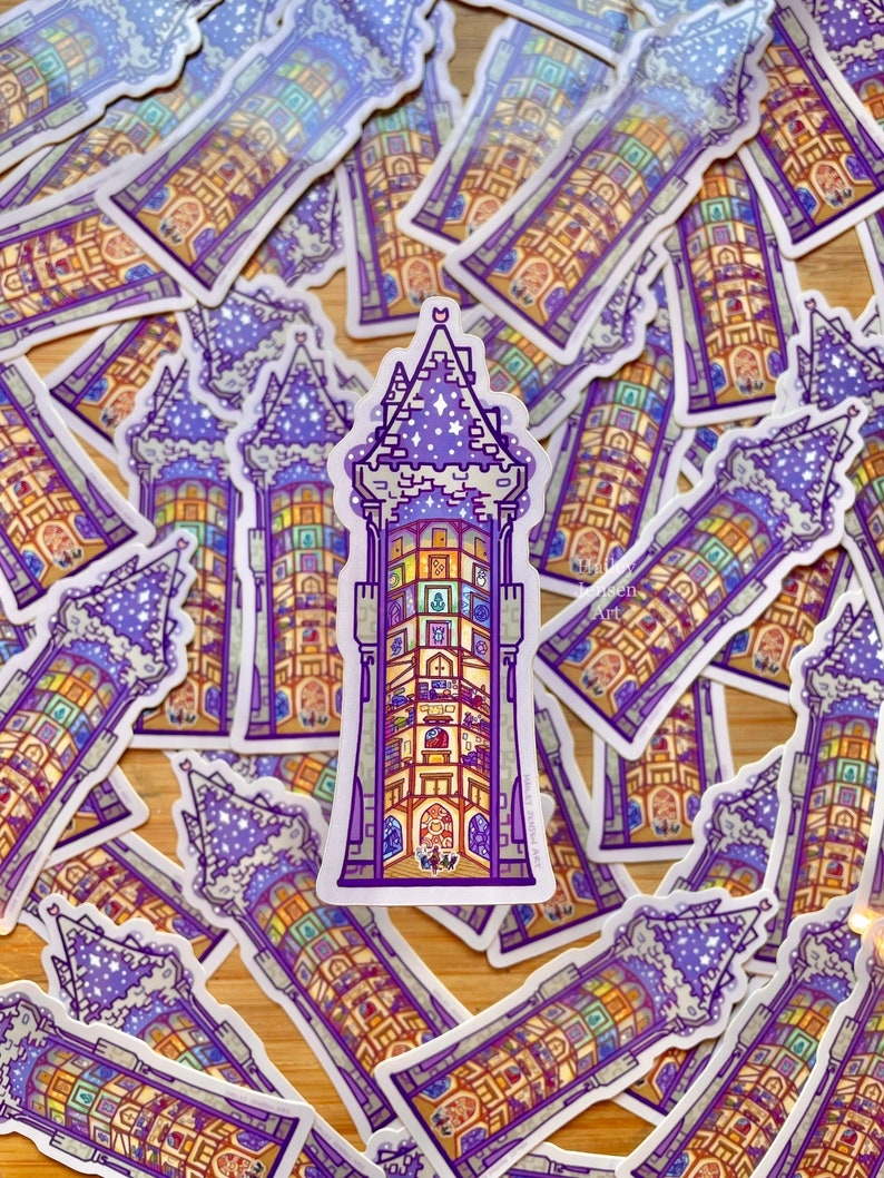 May include: A stack of purple and yellow stickers featuring a detailed illustration of a tower with a star-filled sky. The tower has many windows and a pointed roof.