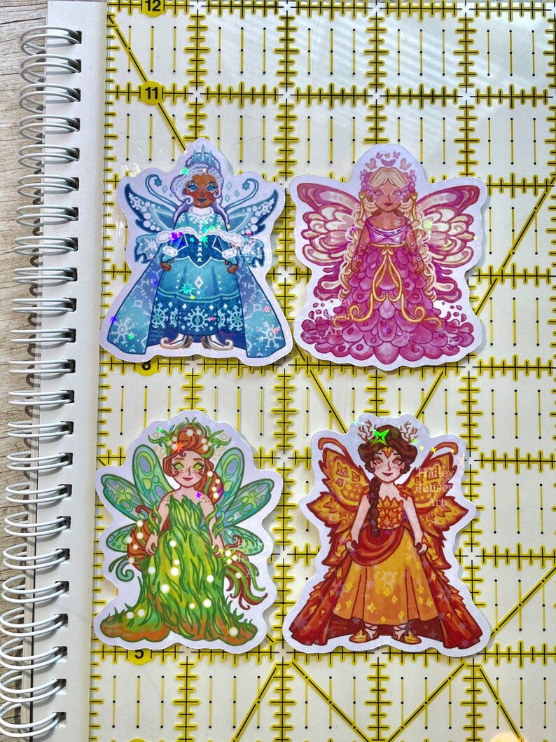 May include: Four colorful fairy stickers. The stickers feature illustrations of fairies in various outfits and colors, including blue, pink, green, and orange. Each fairy has detailed wings and unique attire.