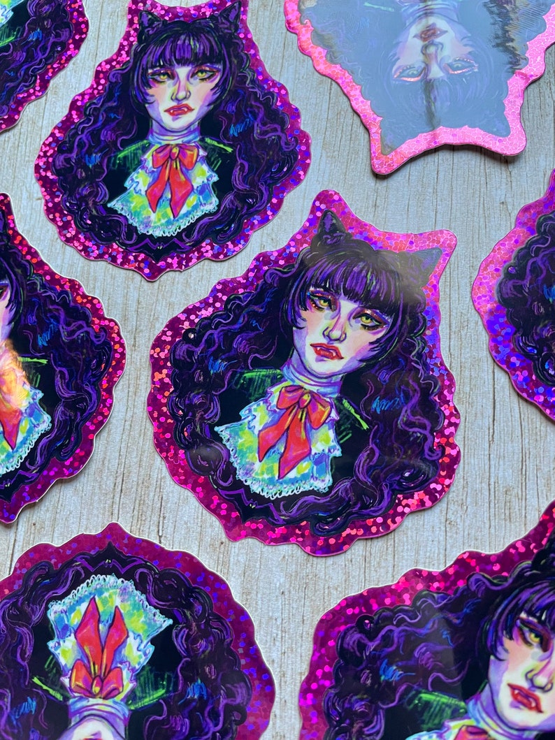 K&ouml;nnte beinhalten: Ein Satz holografischer Aufkleber mit einer Comicfigur mit schwarzen Haaren, violetten Augen und einer roten Schleife. Die Aufkleber befinden sich auf einem rosa Hintergrund.