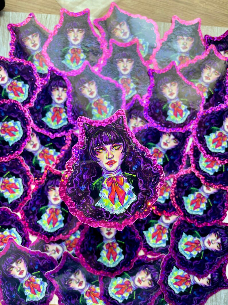 K&ouml;nnte beinhalten: Ein Stapel Aufkleber mit einem Cartoon-M&auml;dchen mit lila Haaren, das ein schwarz-wei&szlig;es Kleid mit einer rosa Schleife tr&auml;gt. Die Aufkleber haben eine glitzernde, irisierende Oberfl&auml;che.