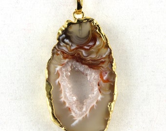 May include: A natural agate pendant with a gold-colored trim and bail. The agate features bands of brown, white, and orange hues, with a central crystal-lined cavity. The pendant is designed for wear as a necklace.