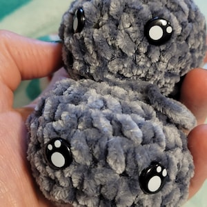 May include: Two gray crocheted plush toys with black eyes and white paw print details. The toys are soft and cuddly.