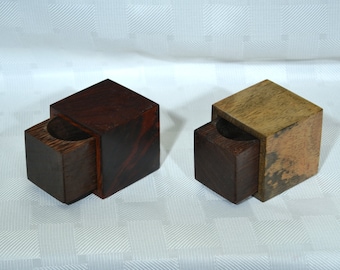 May include: Two small wooden boxes with hinged lids. The box on the left is made of dark wood with a reddish brown hue. The box on the right is made of light wood with a brown and white mottled pattern.