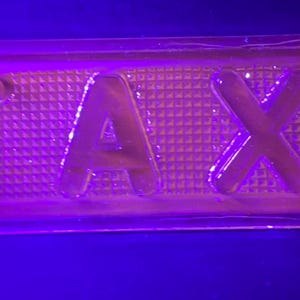 May include: A purple plastic sign with the word "TAXI" embossed on it.