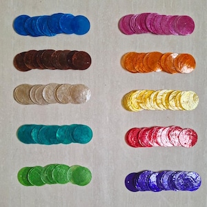 May include: A collection of circular, flat, thin, iridescent shell discs arranged in ten horizontal rows. The colours include blue, pink, brown, orange, beige, yellow, teal, red, green, and purple. Each disc features a small hole for attachment.