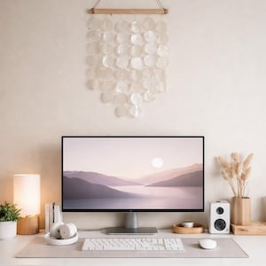 Puede incluir: Un escritorio minimalista para el hogar con un monitor de computadora que muestra un paisaje. Incluye una lámpara, una planta, altavoces, un teclado, un ratón y una decoración de pared hecha de conchas blancas redondas. El escritorio mide 120 cm de ancho.