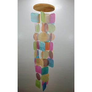 May include: A decorative wind chime featuring a wooden disc at the top and a cascade of iridescent shells in pastel colours. The shells, in various shapes, are strung together to create a hanging ornament. Suitable for indoor or outdoor use, this item is a charming addition.