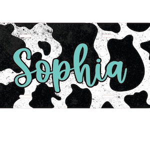 May include: A black and white cow print license plate with the name "Sophia" written in turquoise.