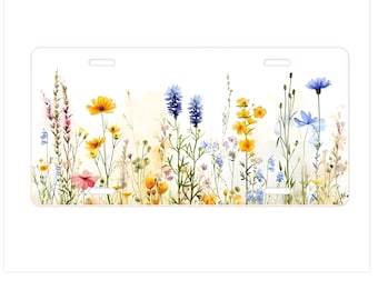 May include: A rectangular license plate featuring a watercolor painting of wildflowers. The design includes yellow, blue, pink, and purple flowers with green stems and leaves against a white background. The plate has three slots for mounting.