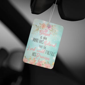 May include: A rectangular air freshener with a floral design and the text "Blessed is she who has believed that the Lord would fulfill his promises to her." The air freshener has a light blue background and pink and peach flowers.