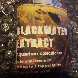 May include: A brown bottle with a white label that reads "BLACKWATER EXTRACT Aquarium conditioner naturally lowers ph add up to 1 tsp per gallon of aquarium water Made in the USA".