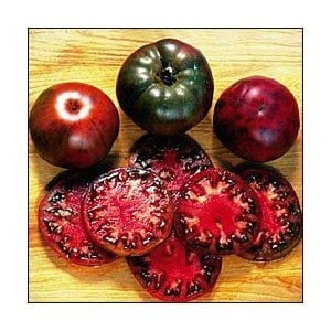Puede incluir: Cuatro tomates negros enteros y varias rebanadas de la misma variedad de tomate. Los tomates son verde oscuro, rojo oscuro y negro. Las rebanadas revelan un interior rojo con vetas negras.