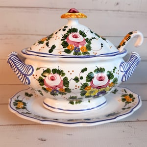 Puede incluir: Una taza de cerámica blanca con un asa negra y el texto "But First, Coffee" en negrita negra. La taza se encuentra sobre un fondo borroso, resaltando su diseño limpio.