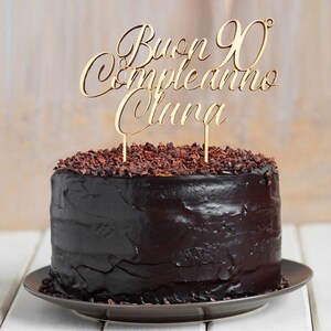 May include: A chocolate cake with a wooden cake topper that says "Buon 90 Compleanno Clara".