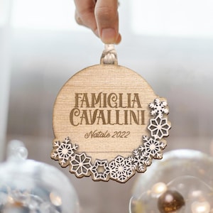 May include: A wooden Christmas bauble with the text "Famiglia Cavallini Natale 2022" and a white snowflake design.