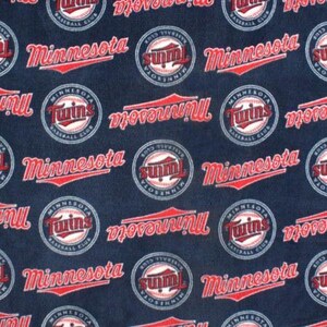 May include: A navy blue fabric with a repeating pattern of red and white baseball-themed logos. The logos include the words "Minnesota Twins" and "2013 Tivey's Summer", along with a baseball and a baseball bat.