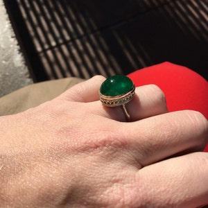 May include: A gold ring with a large, round, green gemstone set in a decorative gold setting.