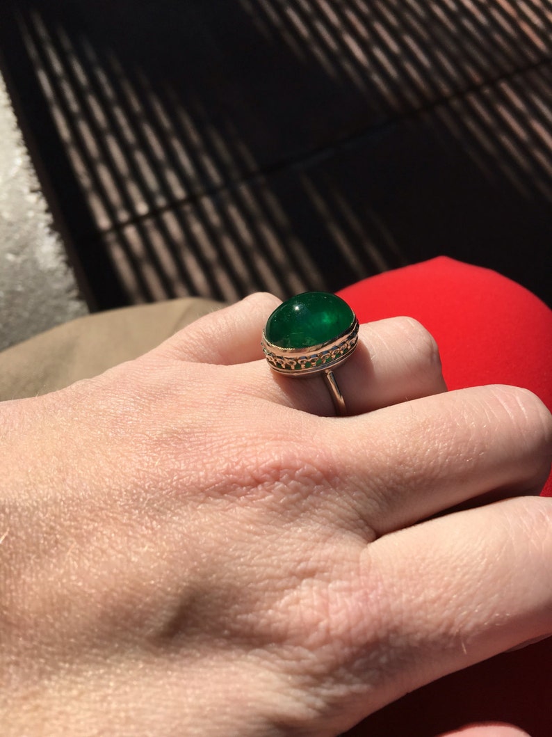 May include: A gold ring with a large, round, green gemstone set in a decorative gold setting.