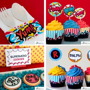 May include: A collection of party supplies featuring comic book themes, including a napkin band with the text YUM!, cupcake wrappers with city skylines, toppers with POW!, WOW!, and RALPH, and a sign labeled SUPERHERO COOKIES with round cookies.