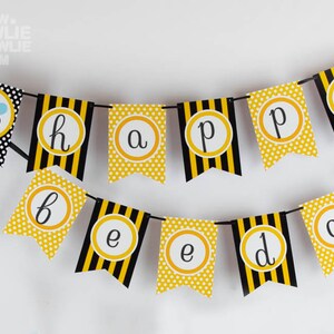 May include: A yellow and black bee-themed banner with the words "happy birthday!" in gold circles. The banner is strung with black string and has a bee illustration at the top.