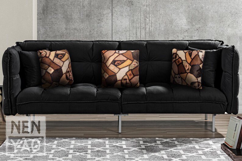 Three handmade square pillows on black suede couch made of minky fleece fabric featuring original patchwork print of multiple shades of human skin and body parts stitched together with haunted faces, ears, elbows, & nipples. Print placement differs.