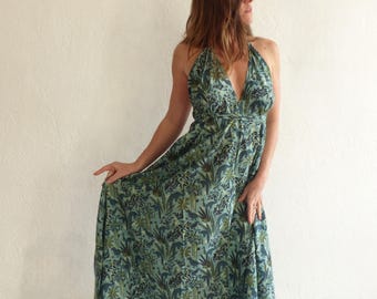 May include: A long, flowing maxi dress with a halter neckline and a deep V-shaped front. The dress is made of a lightweight fabric with a blue and green floral print.