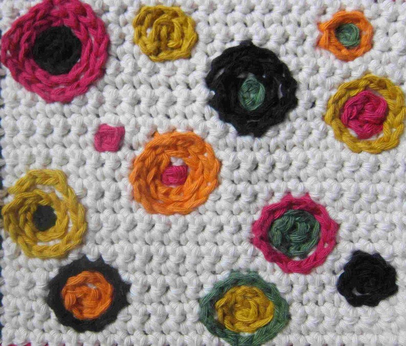 May include: White crocheted fabric with colorful embroidered circles. The circles are in various colors, including pink, yellow, orange, green, and black.