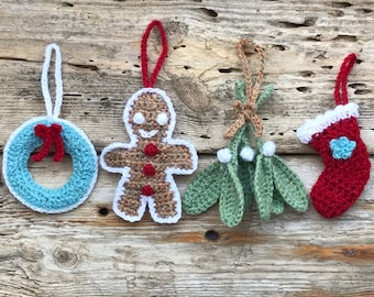 May include: Four crocheted Christmas ornaments: a blue wreath with a red bow, a gingerbread man, a sprig of mistletoe, and a red stocking with a blue snowflake.