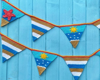 May include: A crocheted bunting with a nautical theme. The bunting is made of blue, white, and yellow yarn and features a starfish, a sun, and waves. The bunting is hanging on a blue wooden background.