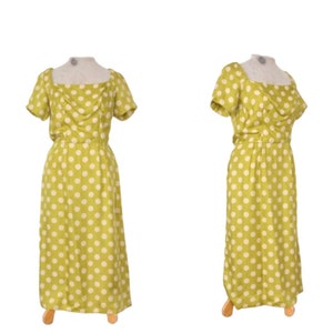May include: A green and white polka dot dress with a square neckline and short sleeves. The dress is fitted at the waist and flows out to the hem.