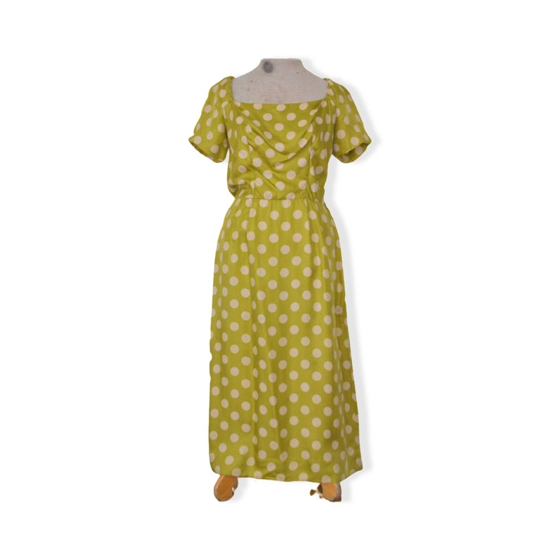 May include: A green maxi dress with white polka dots. The dress has a square neckline and short sleeves.