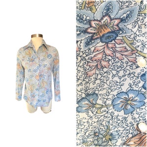 May include: A long-sleeved shirt with a blue, pink, and green floral pattern. The shirt has a collared neckline and button closure.
