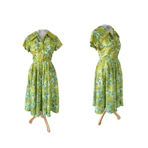 Puede incluir: Un vestido de estampado floral verde y blanco con cuello y mangas cortas. El vestido tiene un corpiño ajustado y una falda completa.