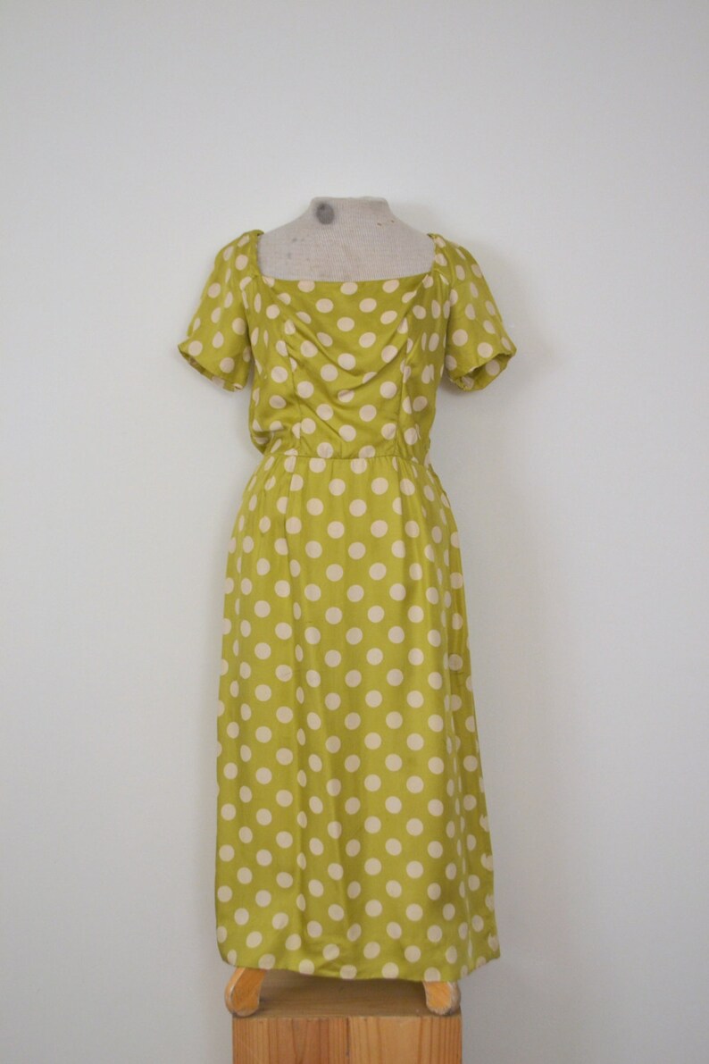 May include: A yellow dress with white polka dots. The dress has a square neckline and short sleeves. It is a midi length dress.