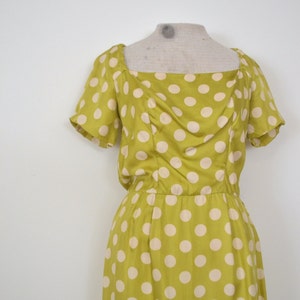 May include: A yellow dress with white polka dots. The dress has a square neckline and short sleeves.